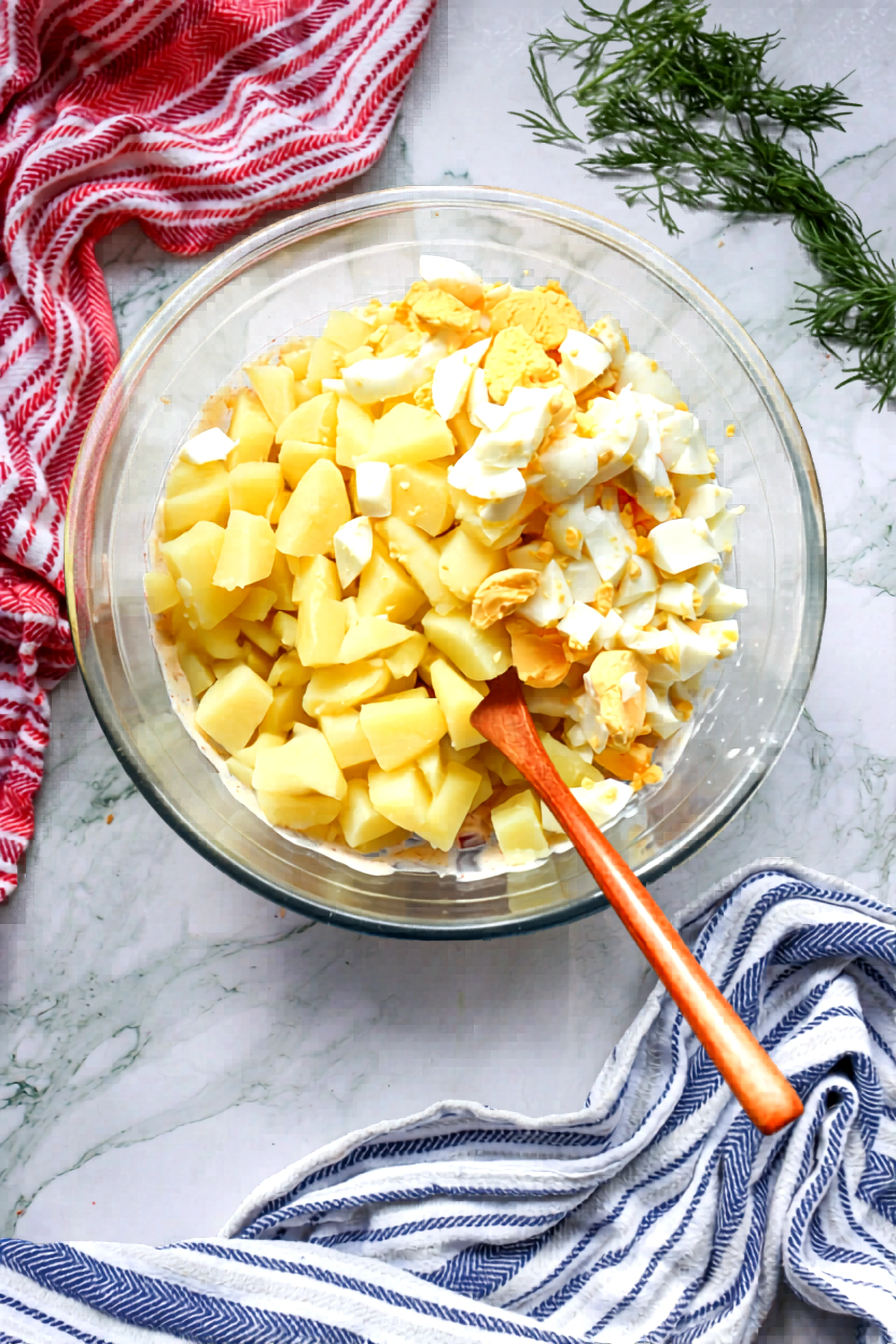 Cooked potatoes and chopped eggs added to the dressing bowl