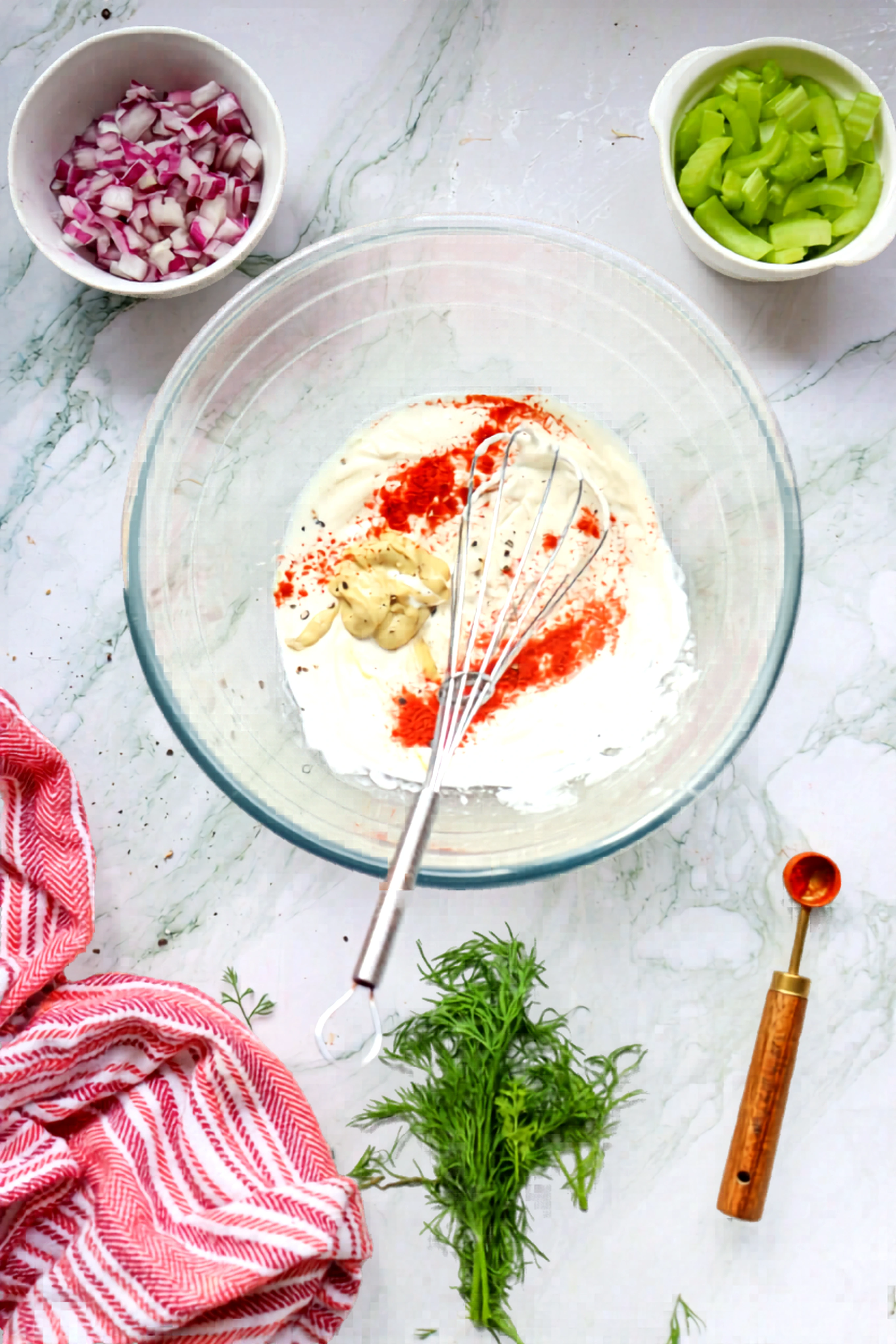 Mayonnaise dressing with mustard and paprika being whisked in a glass bowl
