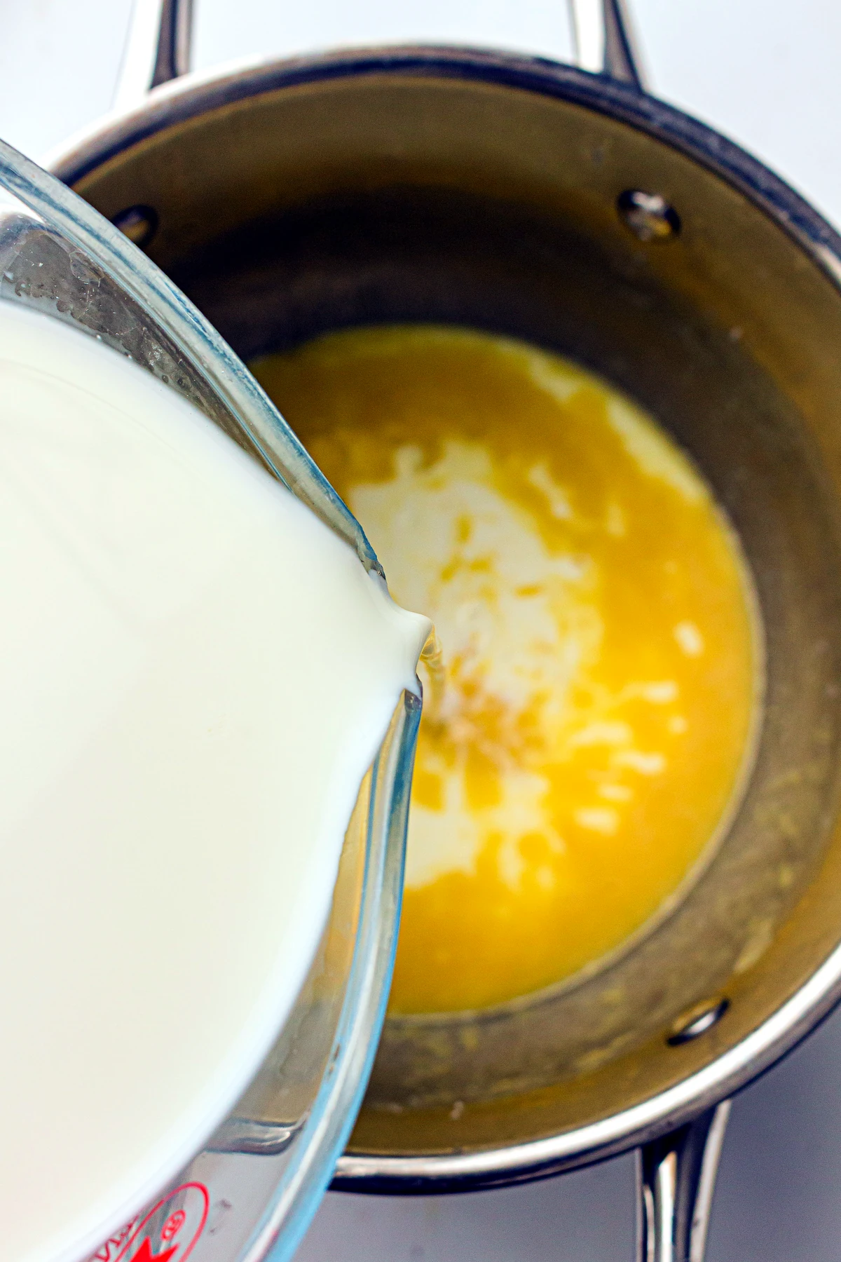 Milk being whisked into mac and cheese sauce
