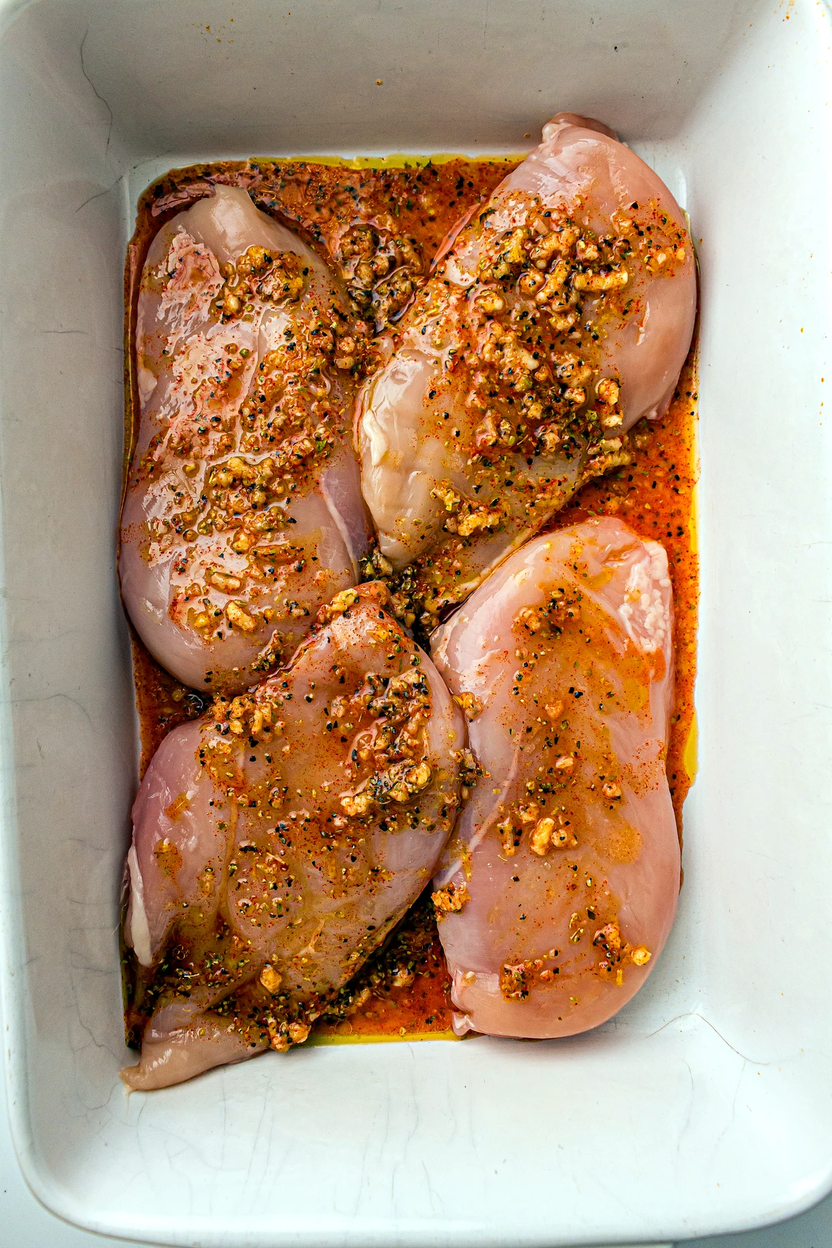 Chicken breasts coated in lemon seasoning in a baking dish