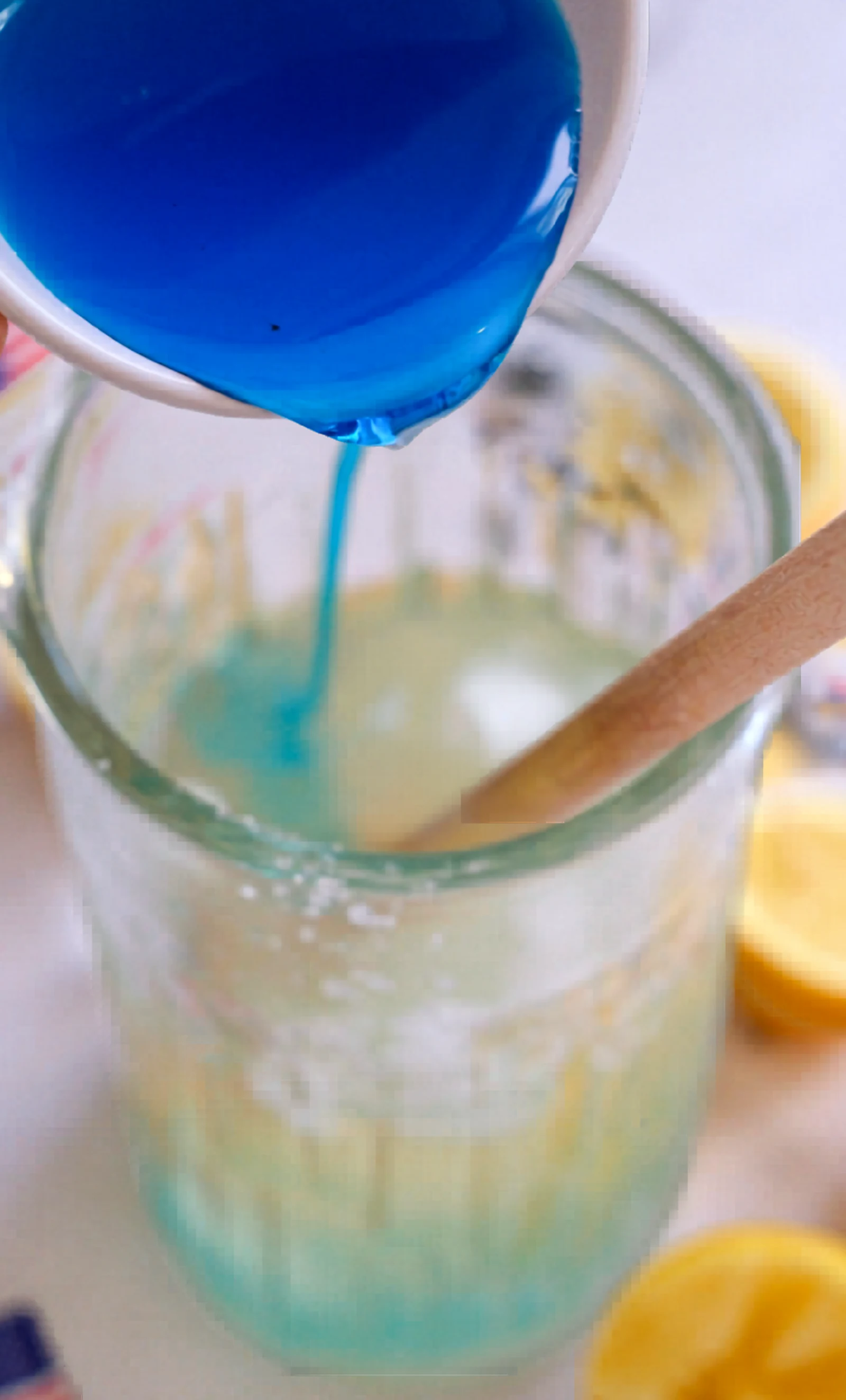 Blue curacao syrup being poured into a mocktail pitcher.