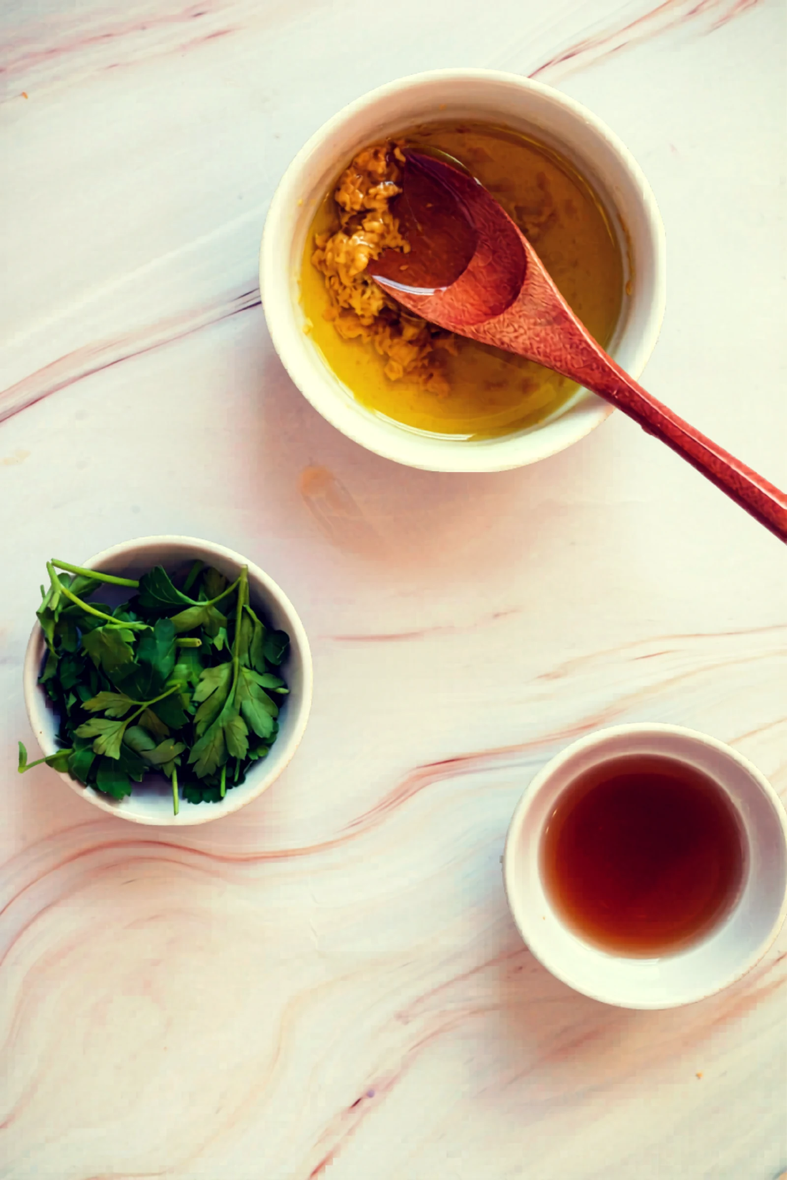 Small bowl of olive oil, vinegar, mustard, and parsley dressing.