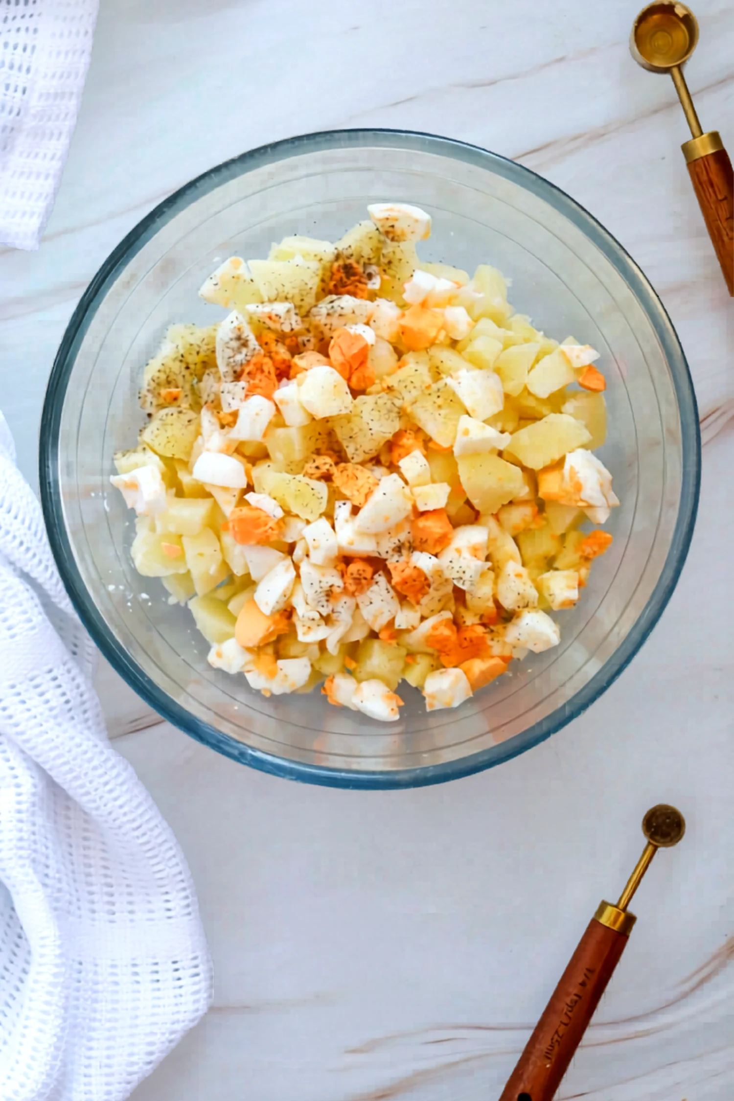 Potatoes and chopped eggs in a bowl with seasonings added