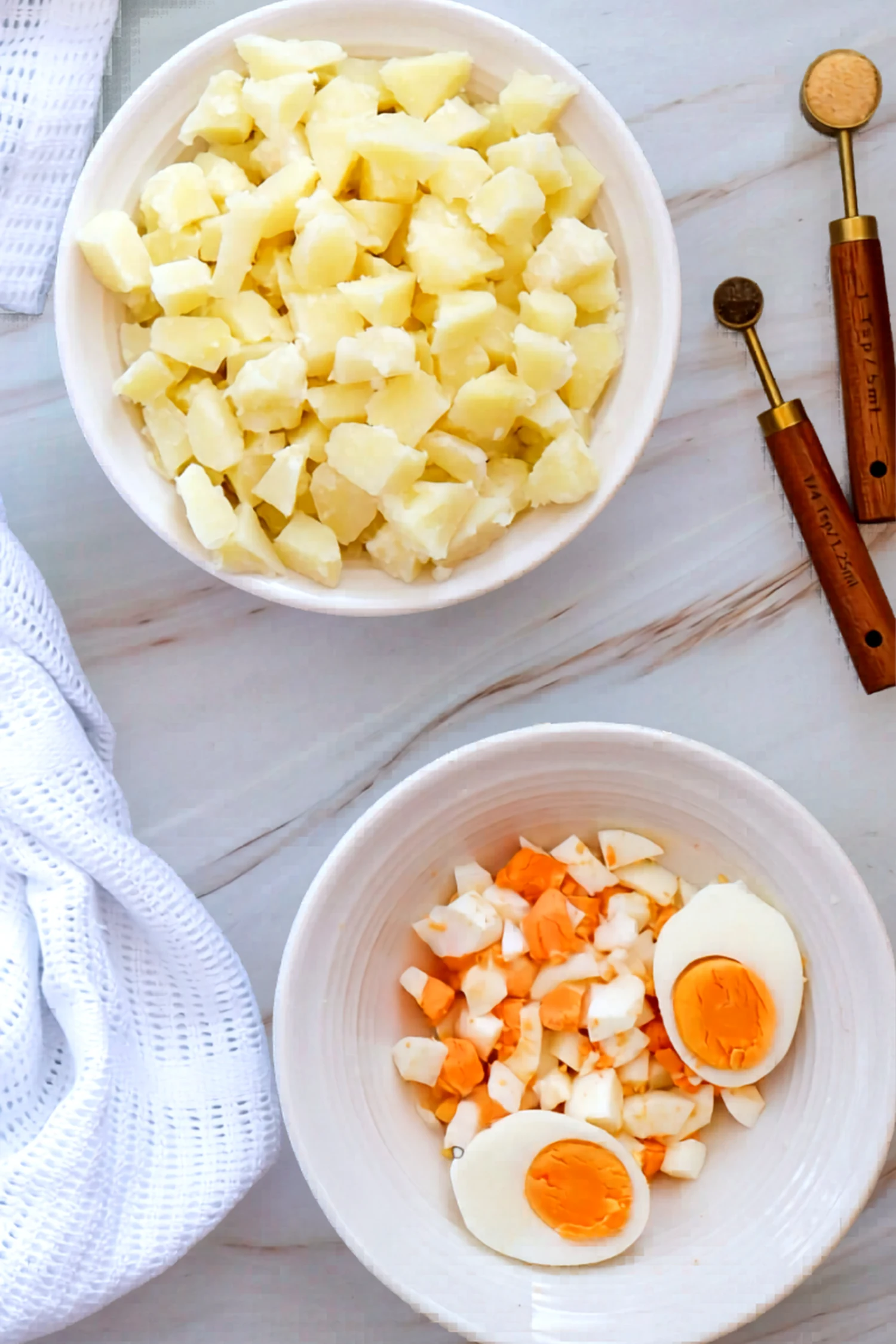 Cooked potatoes and chopped eggs in separate bowls