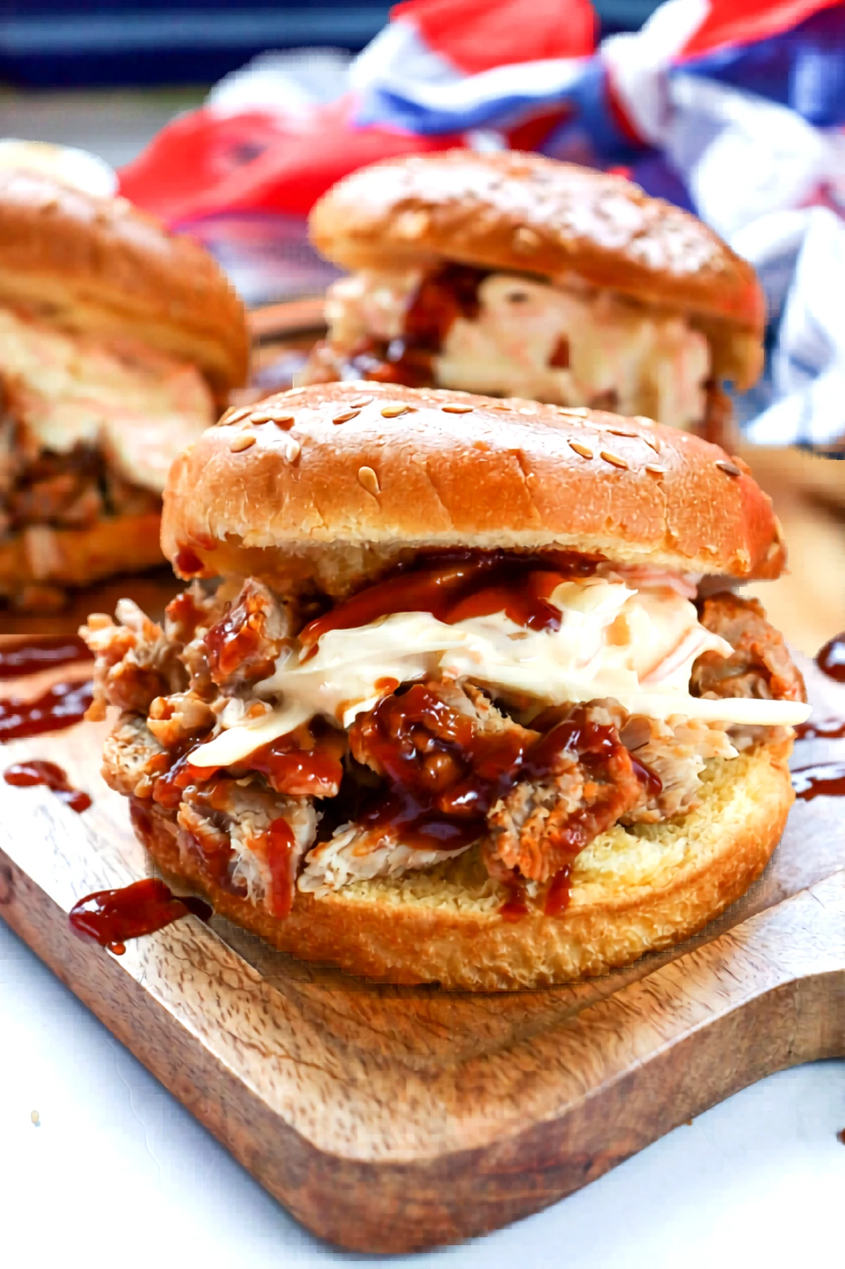 Close-up of a pulled pork barbecue sandwich with slaw and extra sauce.