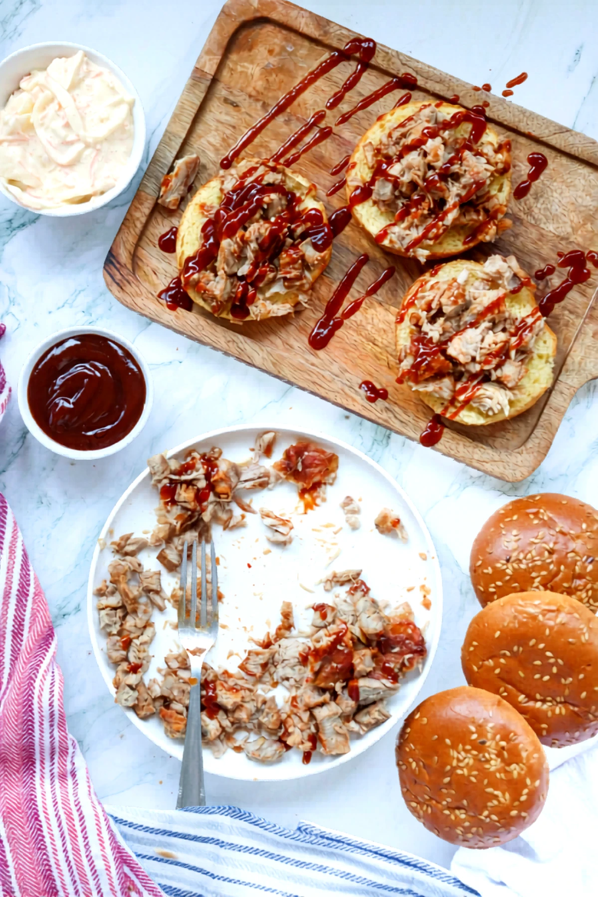 Pulled pork piled onto bun bottoms with extra barbecue sauce drizzled over the top.