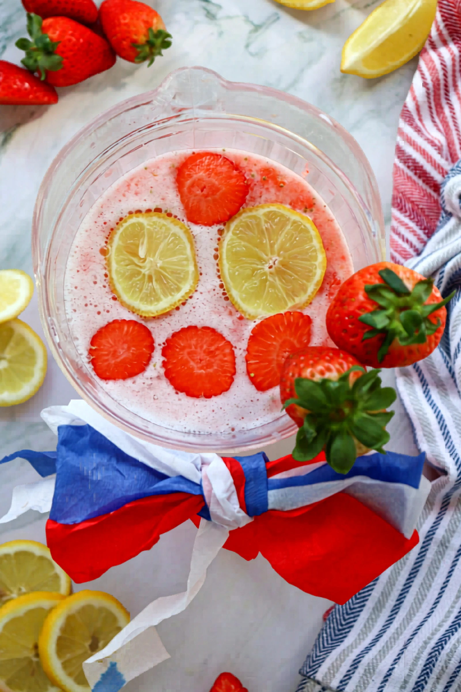 Pitcher of strawberry lemonade garnished with lemon and strawberry slices