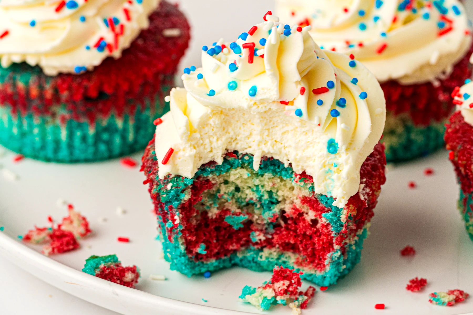 Tie-dye cupcake with a bite taken out on a white plate