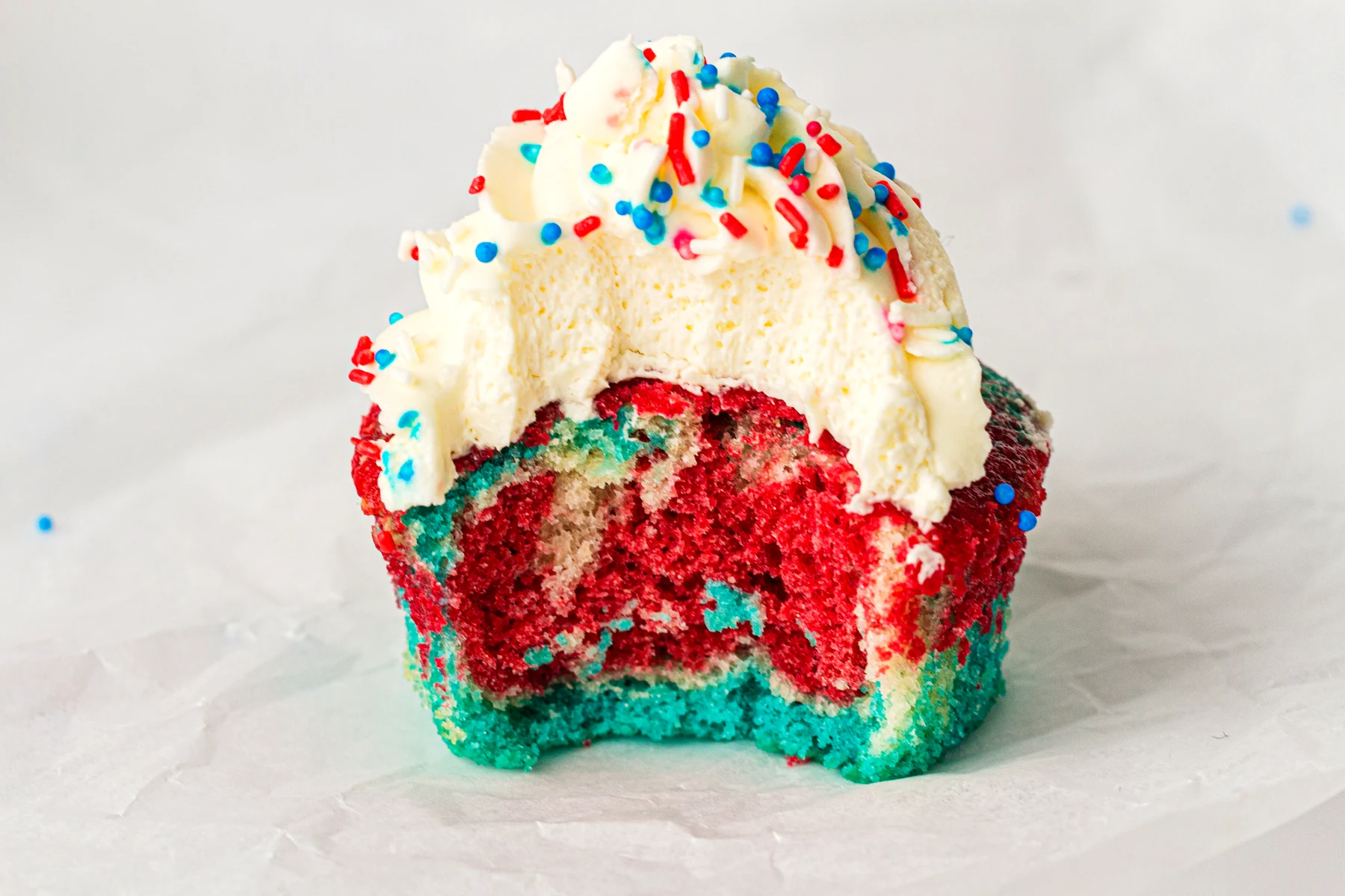 Close crumb shot of a tie-dye cupcake with frosting on top