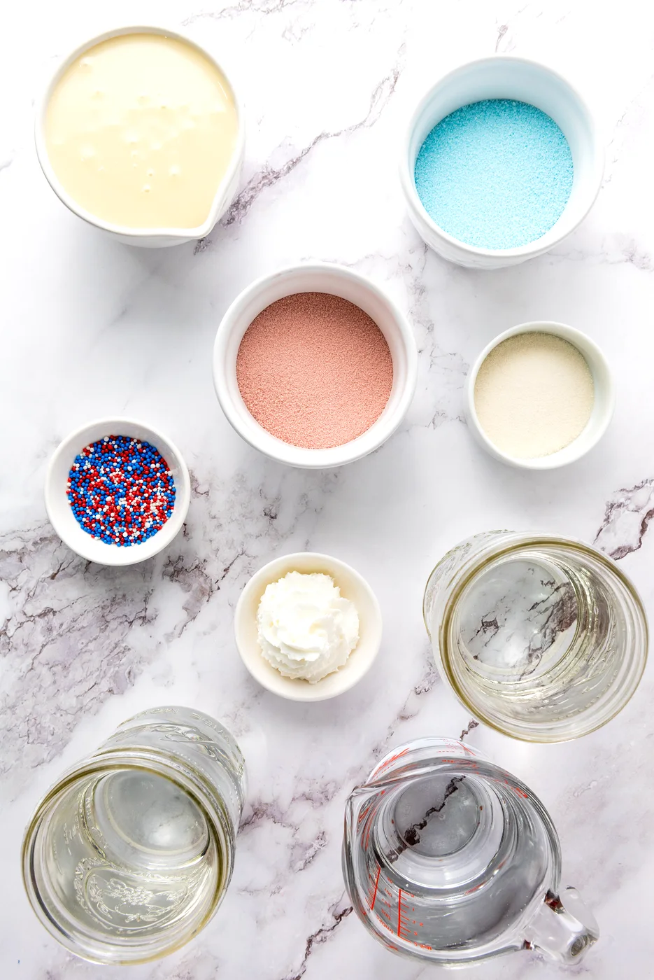 Ingredients for patriotic Jell-O shots arranged in bowls and measuring cups