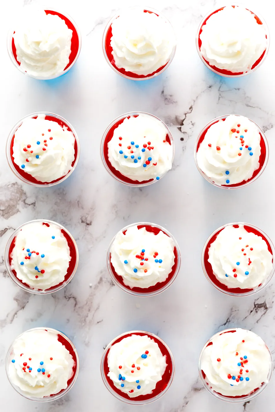 Sprinkles added to whipped cream on patriotic Jell-O shots