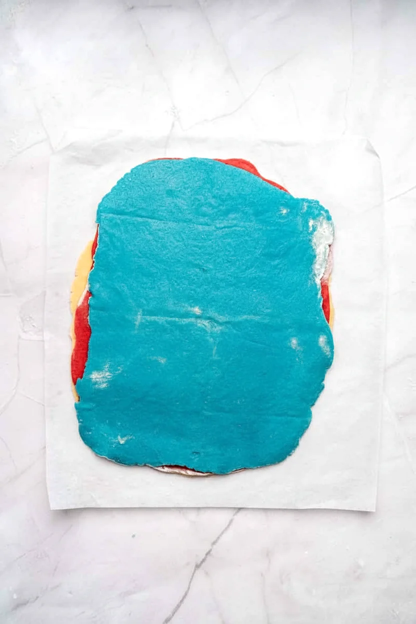 Blue cookie dough stacked over red and plain layers