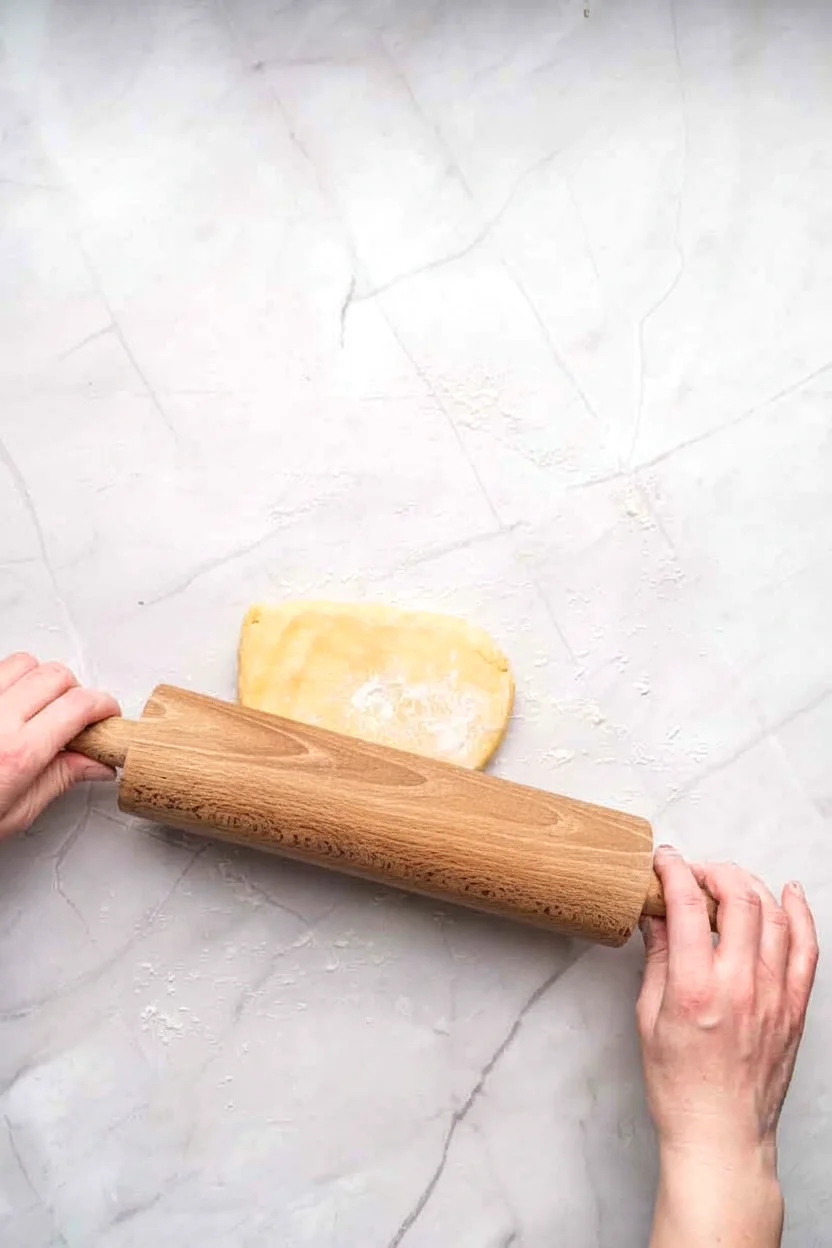 Plain cookie dough being rolled on parchment