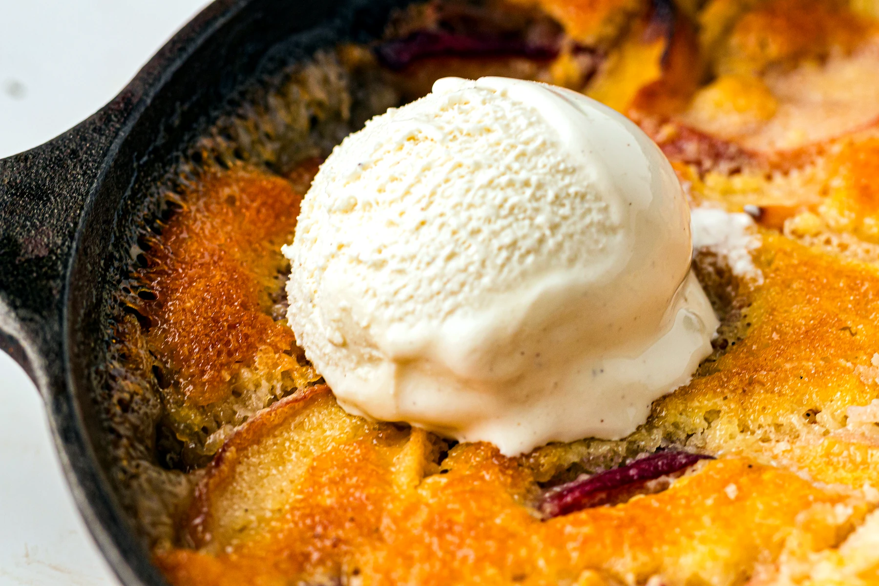 Scoop of peach cobbler topped with vanilla ice cream