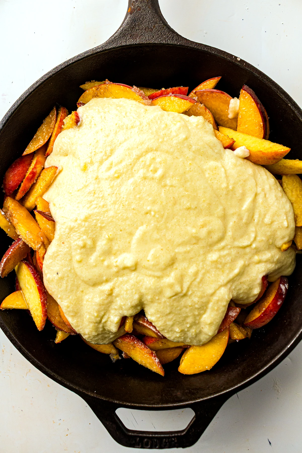 Peach cobbler batter spread over peaches