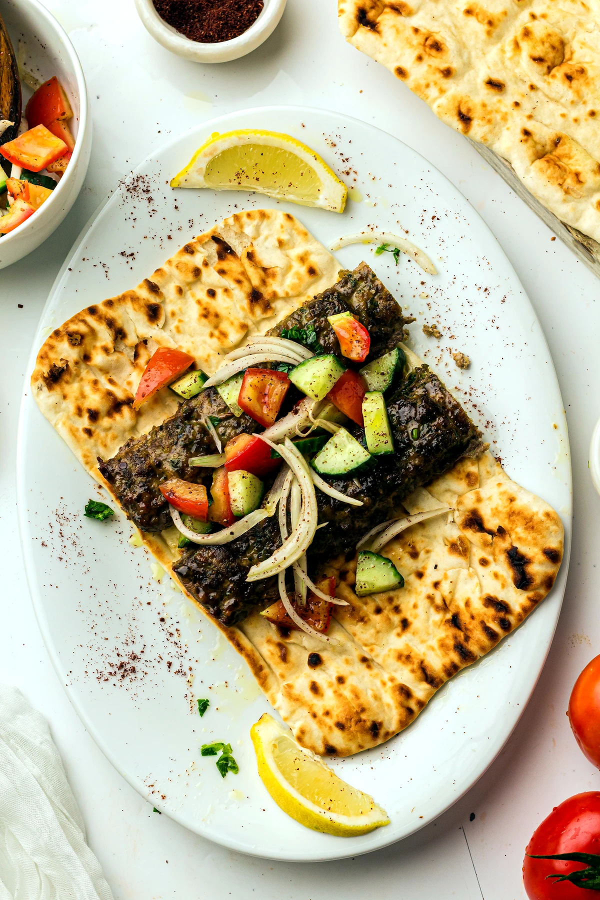 Koftas plated on flatbread with salad