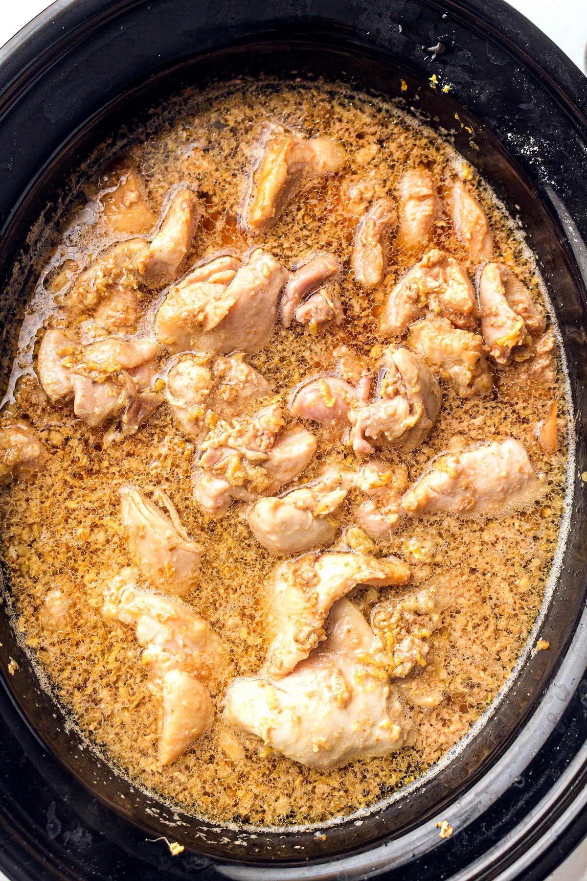 Slow cooker honey garlic chicken cooking in sauce