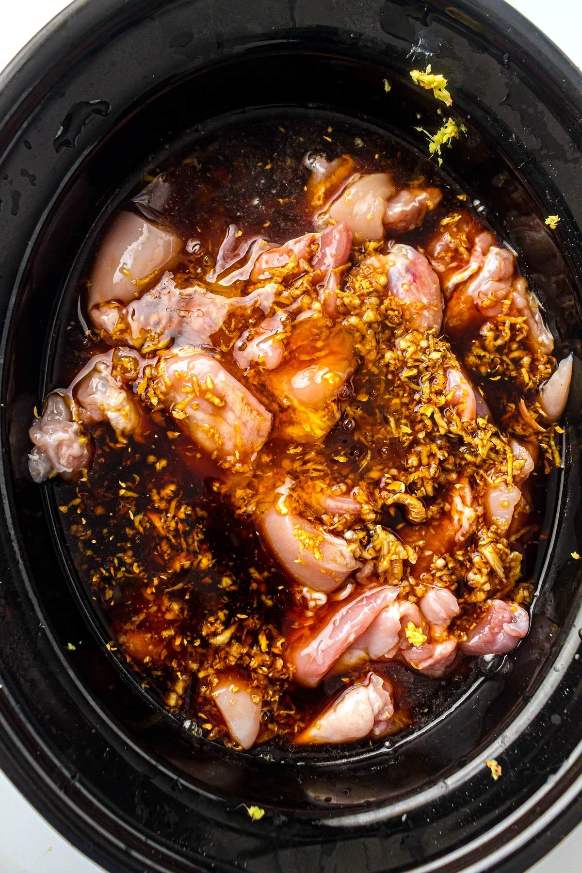 Honey garlic sauce poured over chicken in slow cooker