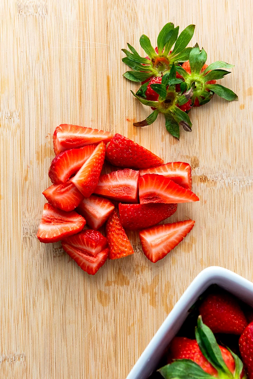 Apple slices strawberries and blueberries being prepped for fruit salad