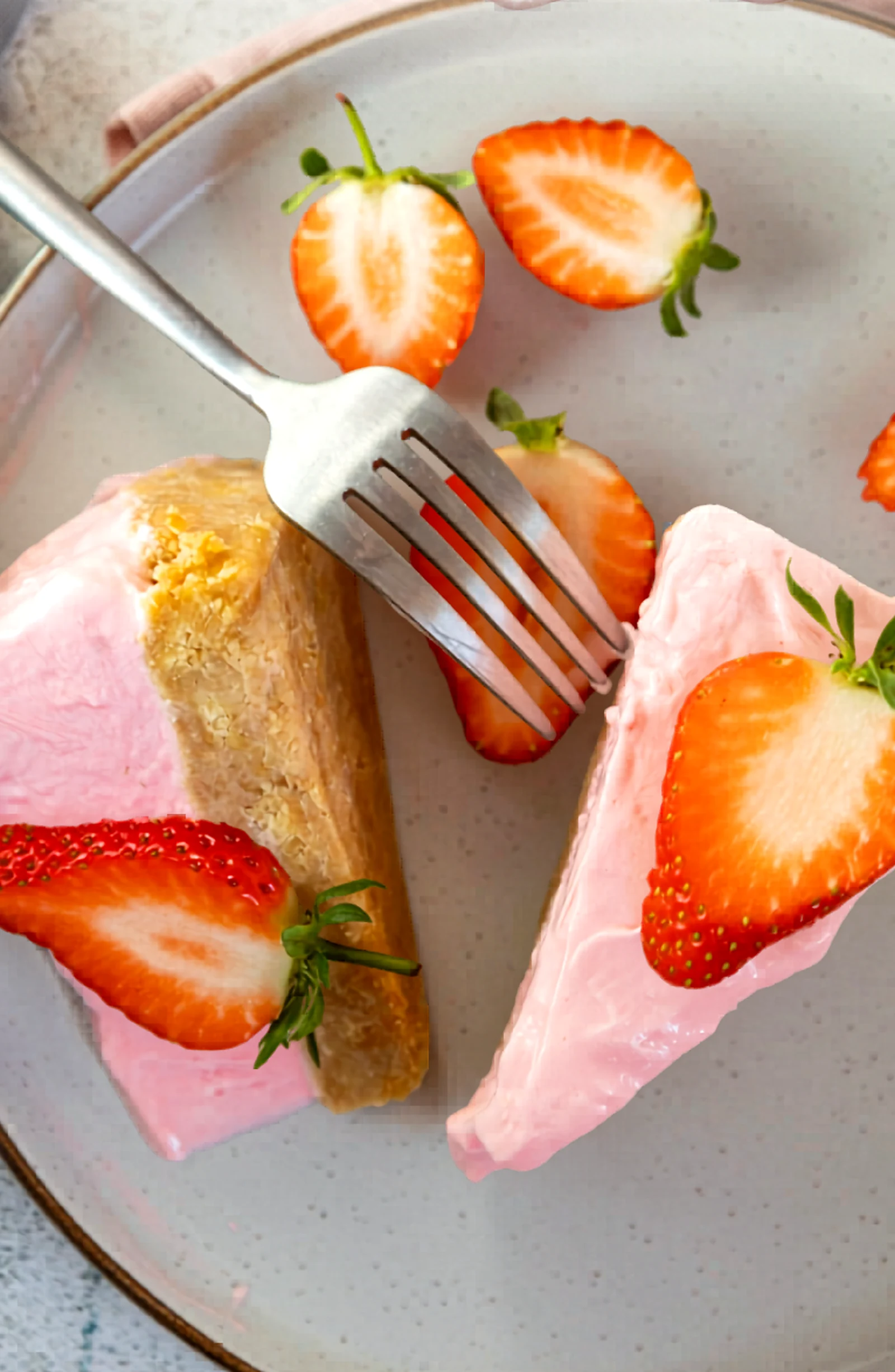 Slice of strawberry no bake cheesecake on a plate with a fork.