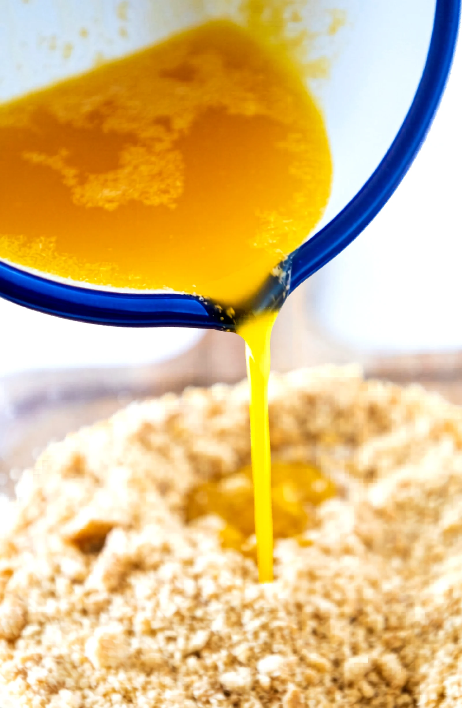 Melted butter being poured over graham cracker crumbs.