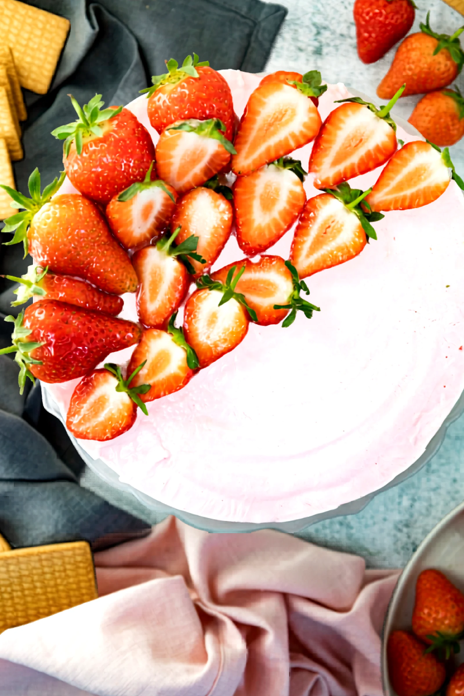 Whole strawberry no bake cheesecake topped with sliced strawberries.