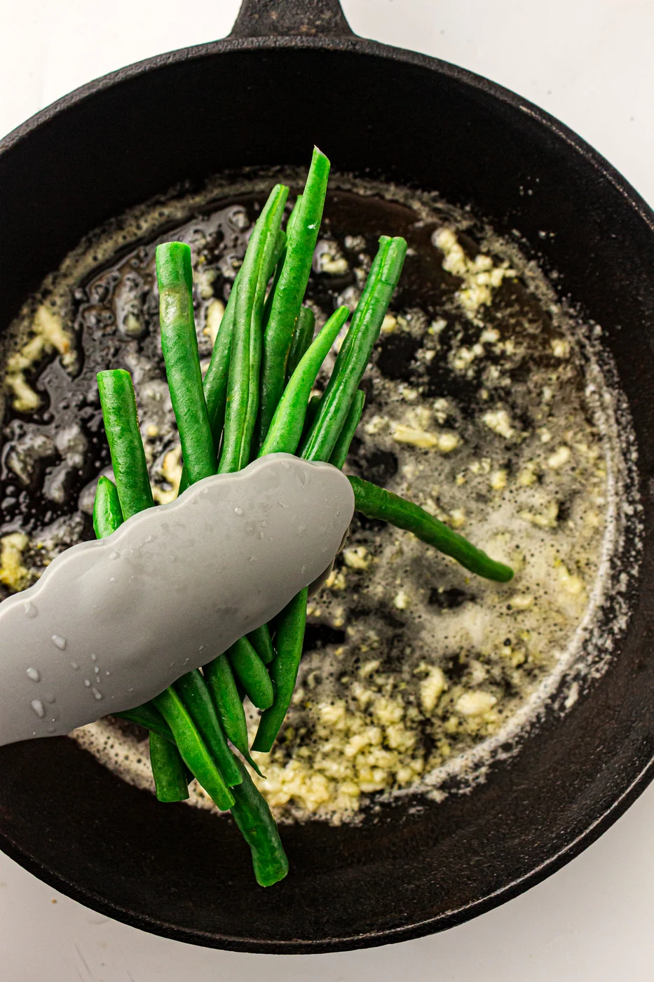 Blanched green beans added to a cast-iron skillet
