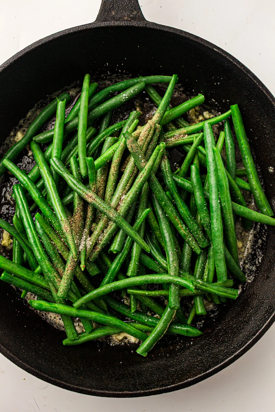 Garlic butter green beans finished in a cast-iron skillet