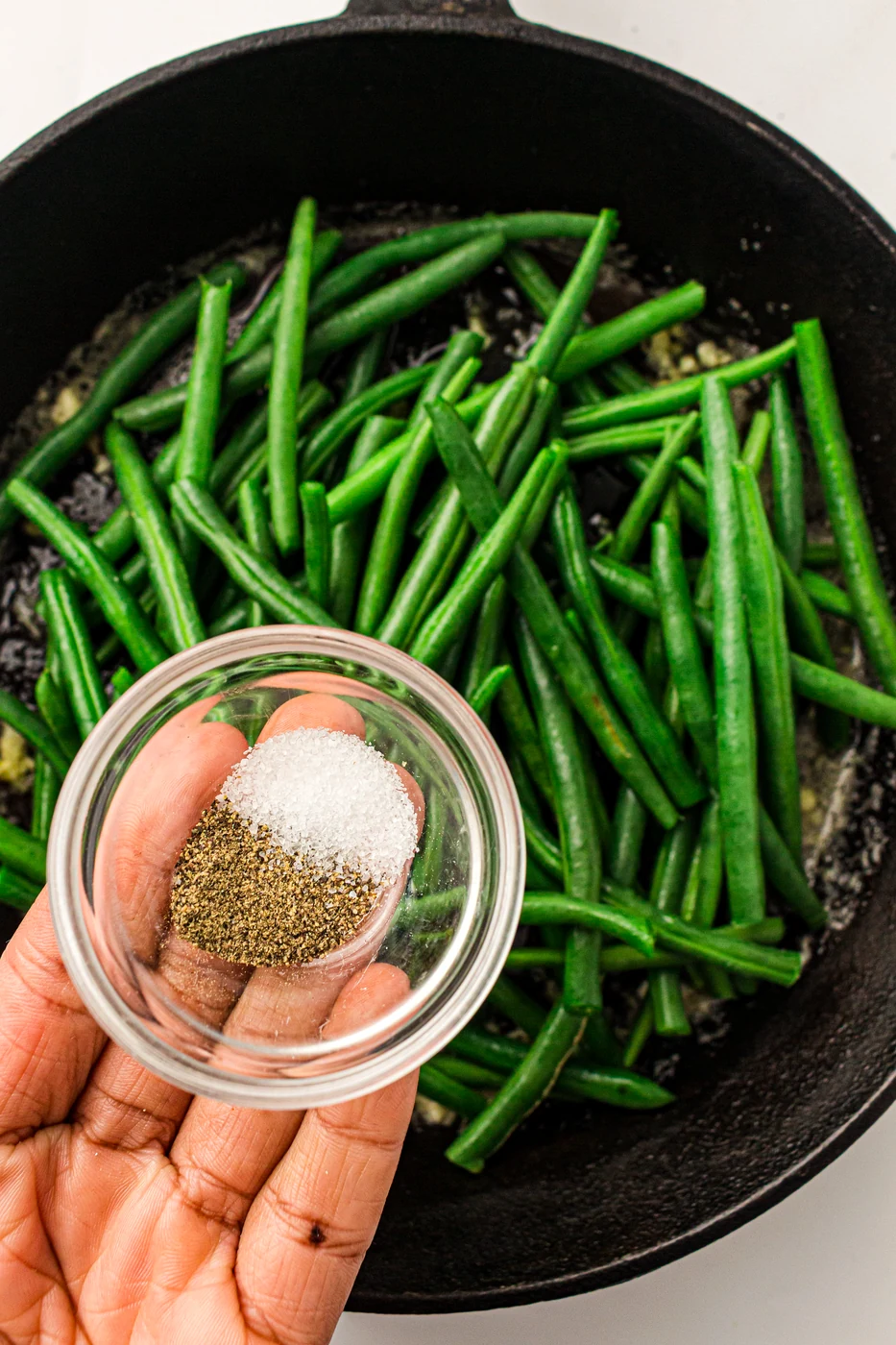 Green beans seasoned with salt and pepper in the skillet