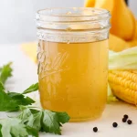 Jar of homemade corn stock with corn parsley and peppercorns