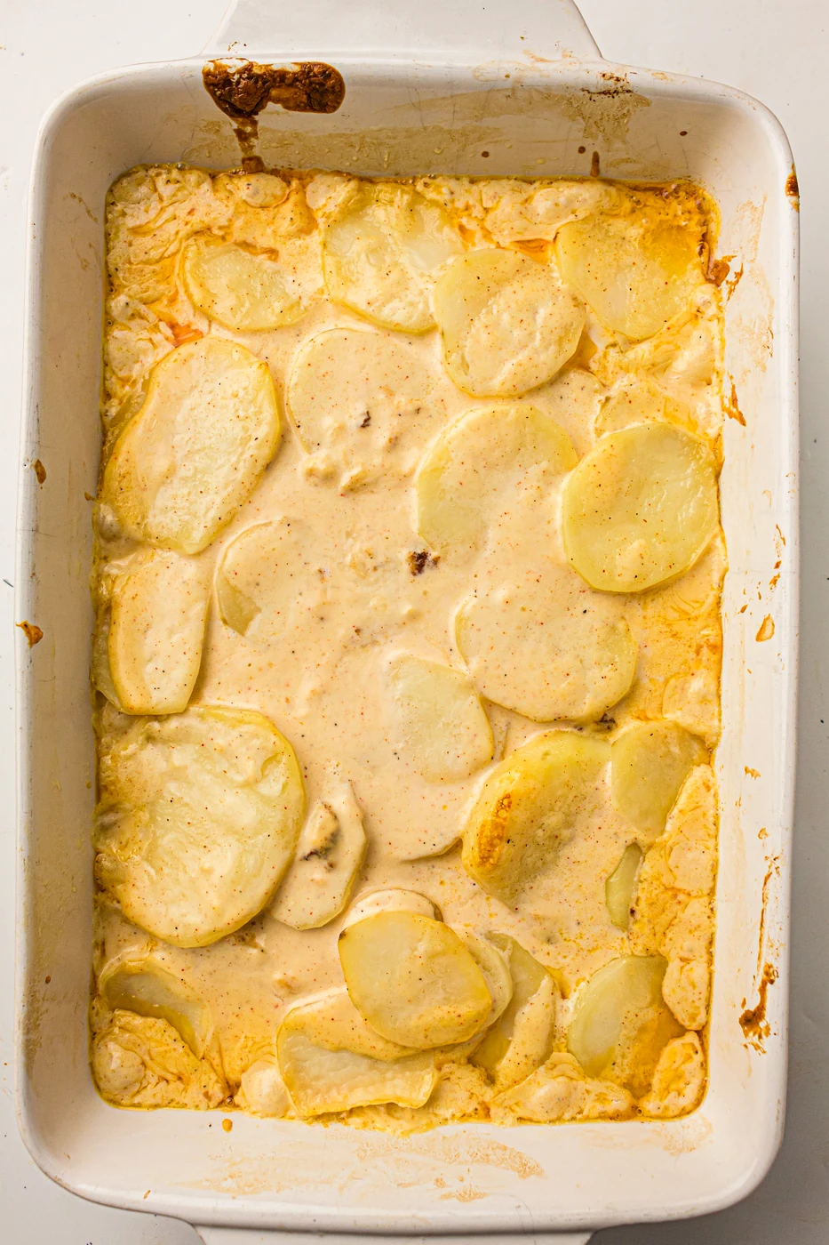Scalloped potatoes softened and bubbling after the covered baking stage