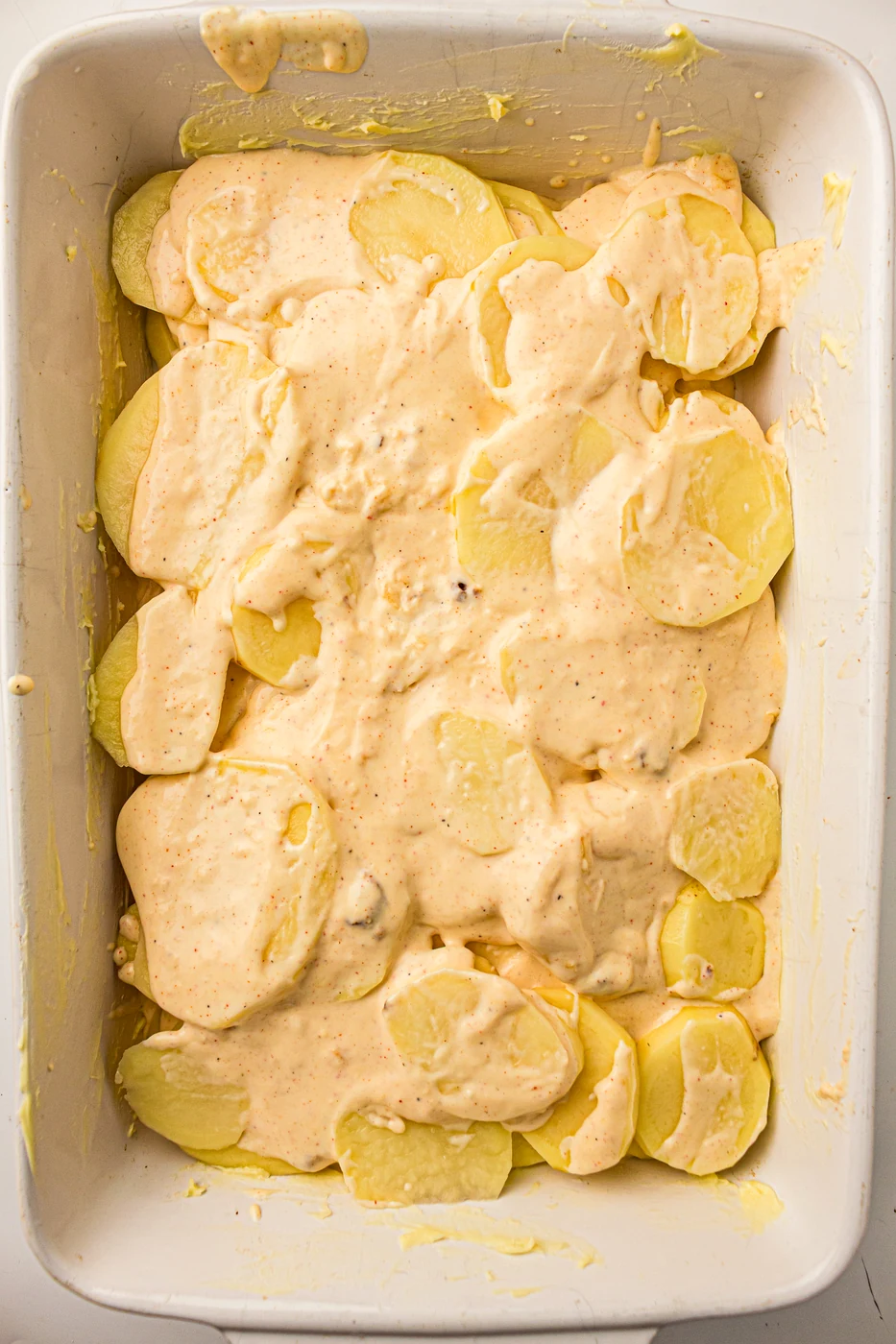 Final layer of potatoes covered evenly with cream sauce