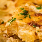 Square close view of creamy scalloped potatoes with golden edges and parsley