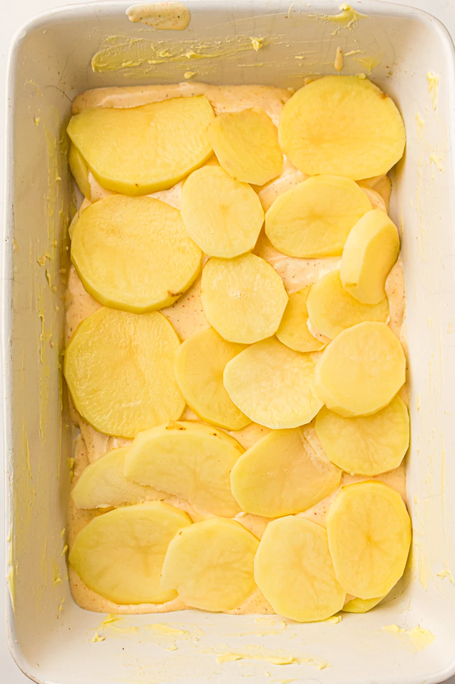 Second overlapping layer of thin potato slices in the baking dish