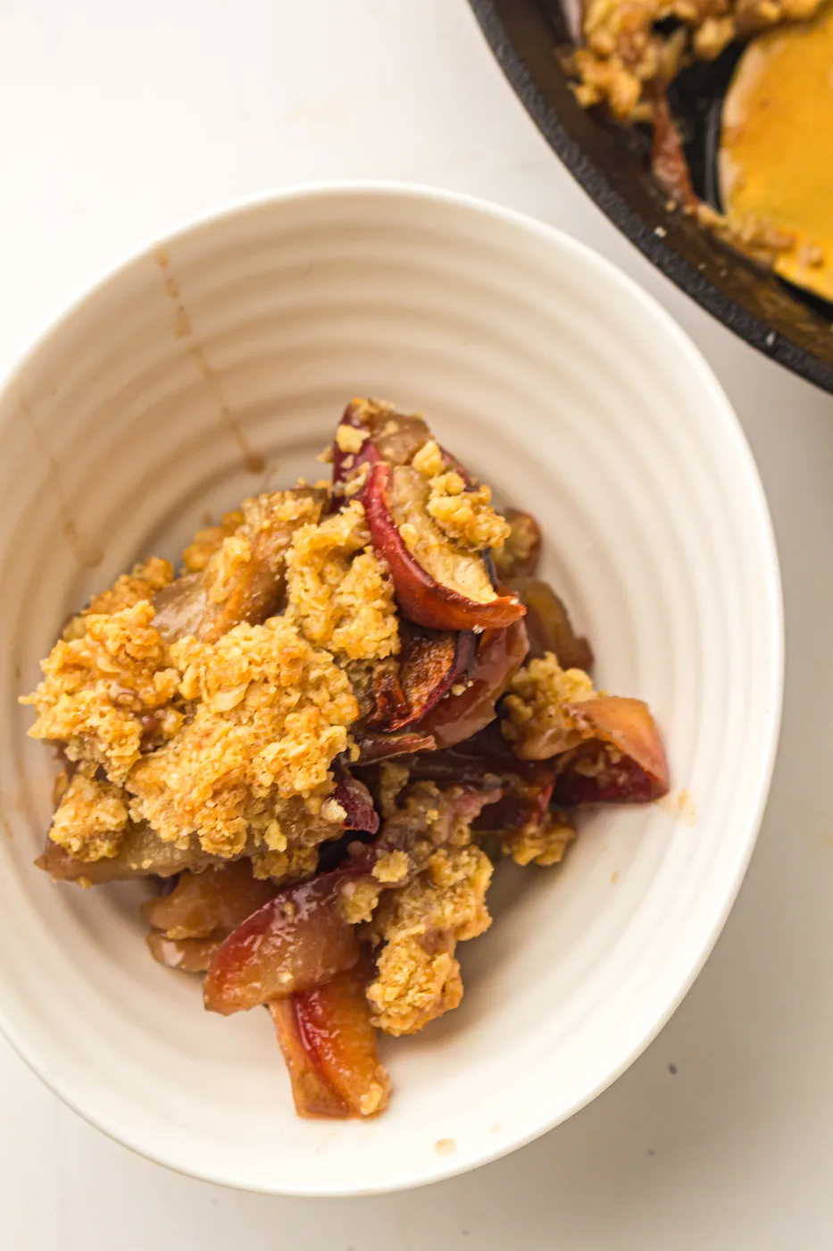 Bowl of homemade skillet apple crisp with visible red-skinned apple slices
