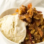 Warm skillet apple crisp served with a scoop of vanilla ice cream